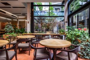 ein Restaurant mit Tischen, Stühlen und Pflanzen in der Unterkunft IOTA Hotel Tbilisi in Tbilisi City