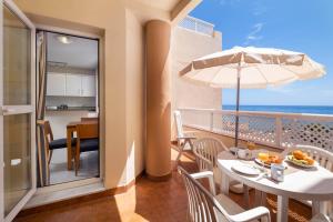 a room with a balcony with a table and an umbrella at Pueblo Marina Seaside Apartaments by Alfresco Stays in Mijas Costa