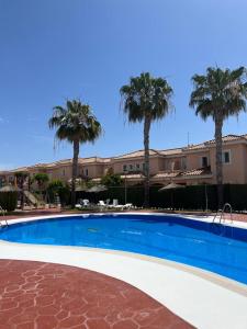 una piscina frente a un edificio con palmeras en House sleeps 6, large pool walk to beach en Vera