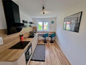 a kitchen with a counter and two chairs in it at Lovely Apartment Vadaš in Štúrovo