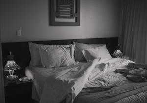 a black and white photo of a bed in a bedroom at Hotel Ponta Verde Praia do Francês in Praia do Frances