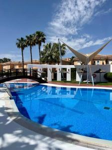 una gran piscina con un puente y palmeras en House sleeps 6, large pool walk to beach en Vera