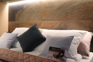 un letto con cuscini bianchi e un libro sopra di The Dome Aparthotel a Satu Mare