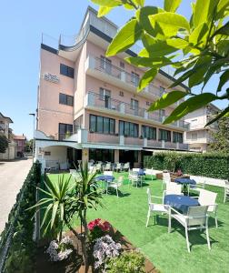 un hôtel avec des tables et des chaises devant un bâtiment dans l'établissement Hotel Bel Sogno, à Rimini