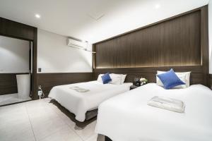 duas camas num quarto de hotel com almofadas azuis em WABA Classic Gwanganri em Busan