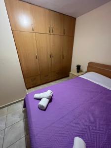 a bedroom with a purple bed with two towels on it at billys apartment in Nea Peramos