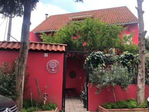 una casa roja con una puerta roja y árboles en Red Goat Hostel, en Tirana