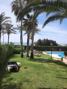 un parque con palmeras y una piscina en Romana Playa 7, Soleuropa en Marbella