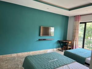 a bedroom with two beds and a tv on a blue wall at PUPON Homestay and Coffee in Quảng Ngãi