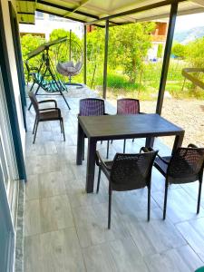 eine Terrasse mit einem Tisch, Stühlen und einer Schaukel in der Unterkunft Airport Guest House in Dalaman