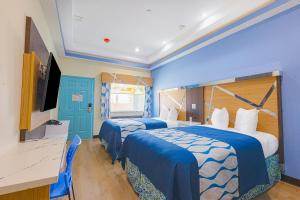 two beds in a room with blue walls at La Vyoma Villas, Westpark Hwy 6 in Houston