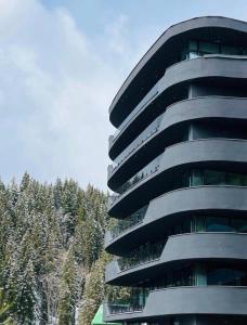 a tall grey building with trees in the background at Bukovel Village Apartments in Bukovel