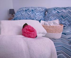 eine rosa Blume auf einem weißen Bett in der Unterkunft Casa Dei Leoni, luminoso open space immerso nel verde in Rom