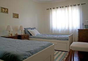 a bedroom with two beds and a window at Barra Azul in Praia da Barra +3 photos