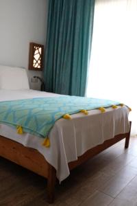 a bedroom with a bed with a blue curtain and a window at Ceneviz Hotel in Adrasan