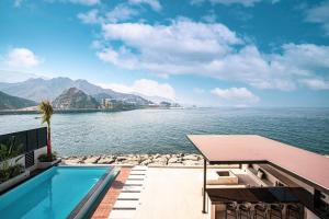 a swimming pool next to a body of water at Luxury Seaview 7 Bedrooms Villa in Fujairah