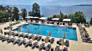 una gran piscina con tumbonas y sombrillas en Hotel Ambasador - Liburnia en Opatija