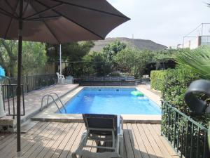 a swimming pool with an umbrella and a chair and a table and a chair at Chalet La Serreta in Alicante