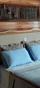 1 cama con cabecero de madera y almohadas azules en Pousada Sentiero, en Urubici