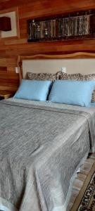 a bed with two blue pillows in a bedroom at Pousada Sentiero in Urubici