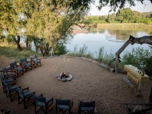 a group of chairs and a bonfire on a beach next to a lake at Hideaways Amava River Lodge, Balule, Greater Kruger in Hoedspruit