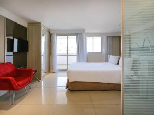 a hotel room with a bed and a red chair at Flat Mercure 1km do Planalto Central h07 in Brasilia