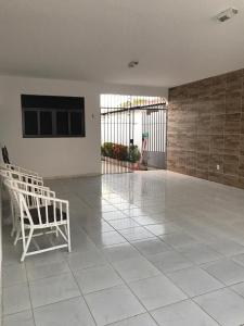a room with a white chair on a tiled floor at Excelente casa 300m2 em Bairro Nobre perto de tudo in Natal