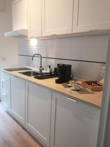 uma cozinha com armários brancos, um lavatório e um balcão em So Fine Petruzzelli flat em Bari