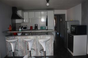 a kitchen with three white stools in front of a counter at Gîte de la Ballade in François