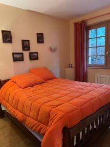 an orange bed in a bedroom with a window at Chalet cerdan typiques a Dorres proche de Font-Romeu in Dorres