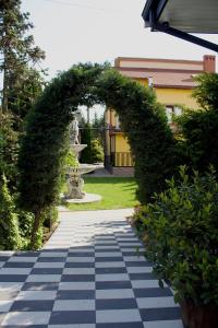 une arche dans un jardin avec une statue en arrière-plan dans l'établissement Forsage Hotel, à Oujhorod