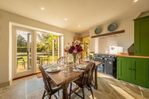a kitchen with a wooden table and some green cabinets at Hensill Farmhouse in Hawkhurst