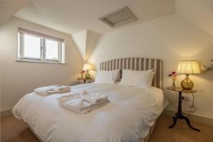 a bedroom with a white bed with two towels on it at Hensill Farmhouse in Hawkhurst