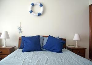 a bed with blue pillows and a wreath on the wall at Barra Azul in Praia da Barra