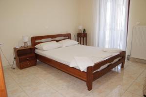 a bedroom with a bed with a wooden frame and a nightstand at Τακης in Xiropigado