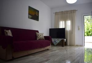 a living room with a purple couch and a tv at Garden House - Kastri Crete in Kastrí