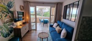 a living room with a blue couch and a table at Agay Cap Esterel Village Allée Fleurs - F2 Clim vue golf et mer - Grande terrasse plein sud in Agay - Saint Raphael