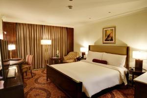 a hotel room with a large bed and a desk at Pearl Continental Hotel, Lahore in Lahore