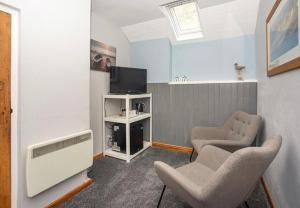 uma sala de estar com duas cadeiras e uma televisão em The Wylfa em Abersoch
