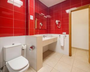 a bathroom with a toilet and a sink and red tiles at ILUNION Costa Sal Lanzarote in Puerto del Carmen