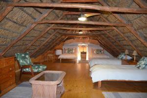 a attic room with two beds and a chair at Heiveld Farm Cottages in Ceres