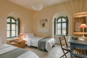 a bedroom with two beds and a desk and two windows at The Tower House in Kardamyli