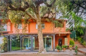 uma casa laranja com uma árvore em frente em Casa Dei Leoni, luminoso open space immerso nel verde em Roma