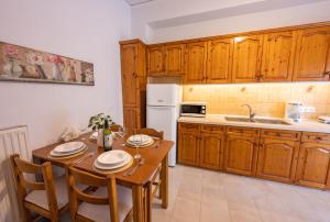 La Casa Di Volpe في مدينة كورفو: مطبخ مع طاولة وكراسي خشبية ومطبخ مع ثلاجة