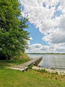a dock on a lake with a cloudy sky at Ferienhaus Blick auf die Müritz in Sietow