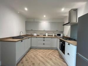 a kitchen with white cabinets and wooden floors at Beach retreat! in Pakefield