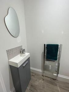 a bathroom with a sink and a mirror and a chair at Beach retreat! in Pakefield