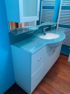 a blue bathroom with a sink and a mirror at Appartamento Andrew’s house con parcheggio privato in Anzola dell'Emilia