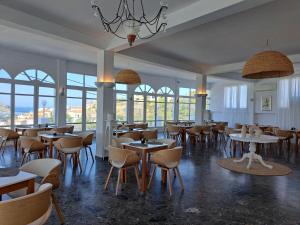 un restaurante con mesas, sillas y ventanas en Paradise Art Hotel en Andros