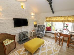 a living room with a television and a table with a chair at Primrose Cottage in Tenby